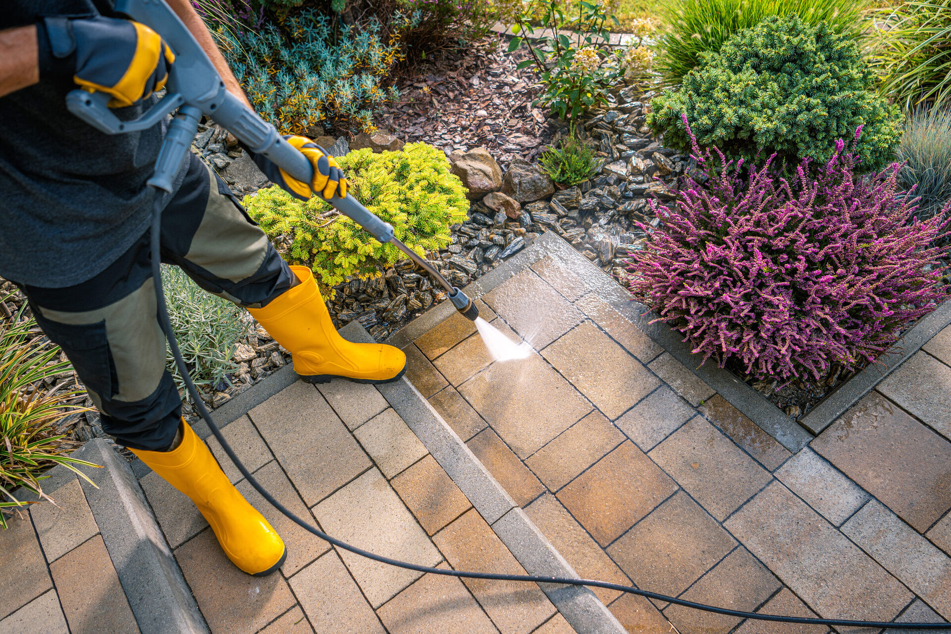 Technician pressure washing a residential concrete driveway